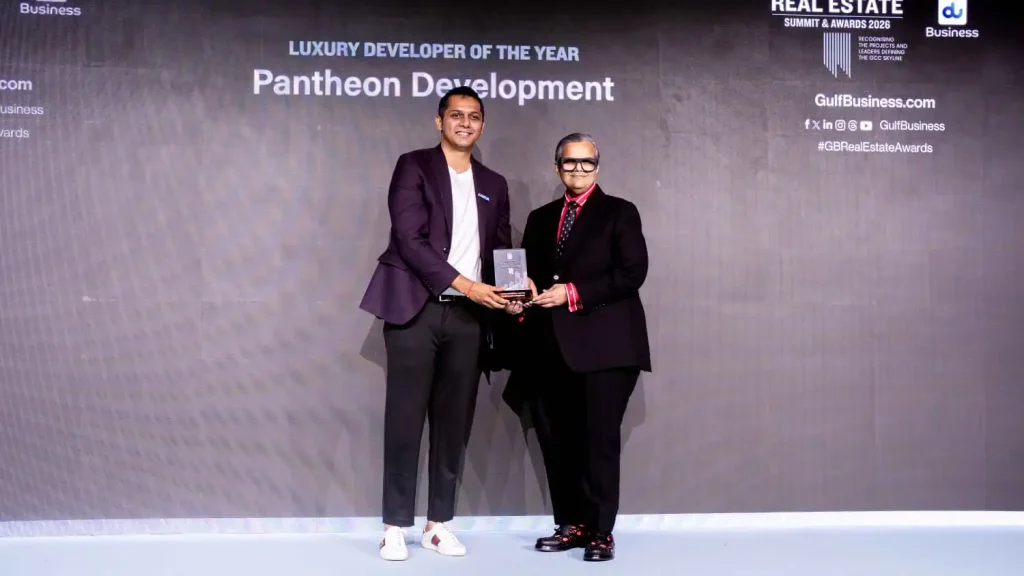 Two men on a stage exchange a trophy during an awards ceremony, with a banner reading 'Luxury Developer of the Year Pantheon Development'.
