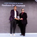 Two men on a stage exchange a trophy during an awards ceremony, with a banner reading 'Luxury Developer of the Year Pantheon Development'.